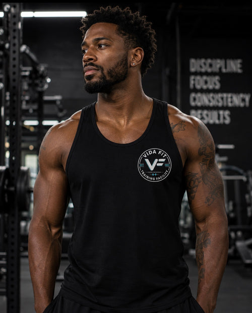 Man wearing black Vida Fit Tank Top in gym with Discipline Focus Consistency Results wall