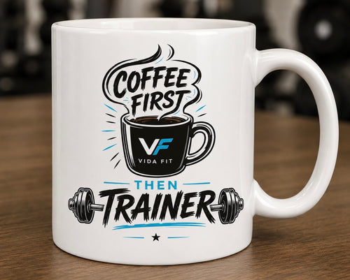 Coffee First Then Trainer white ceramic mug with Vida Fit logo on wooden surface