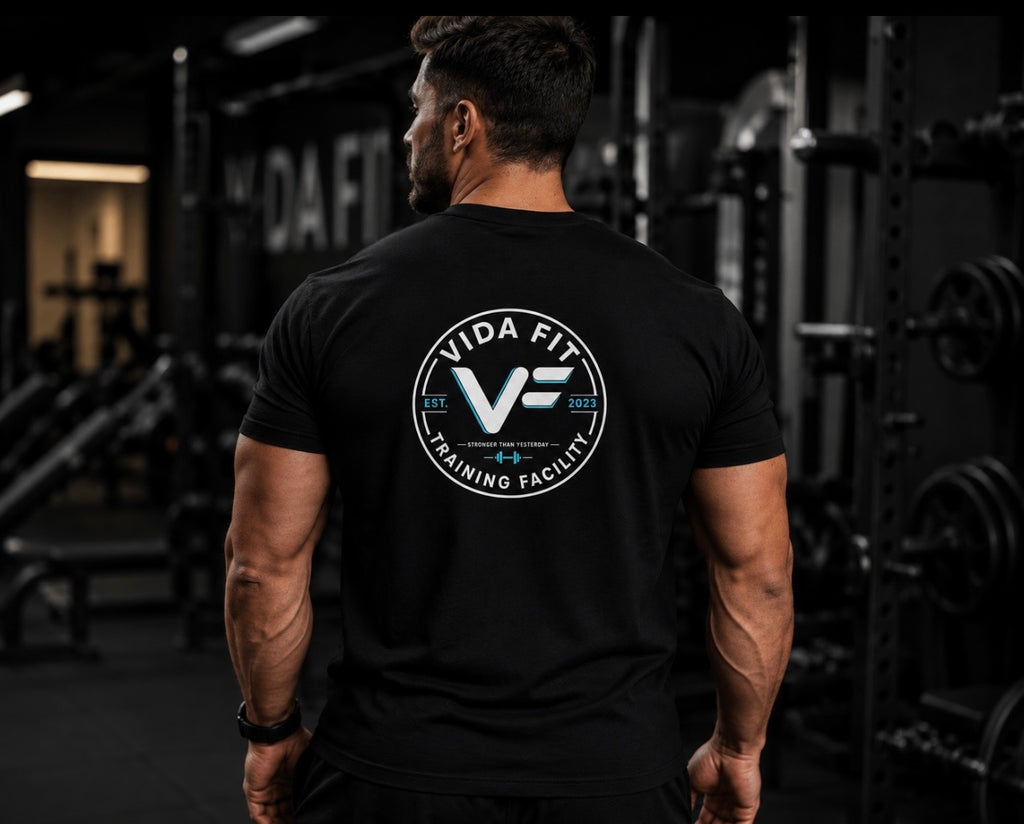 Man wearing black Vida Fit Classic Tee showing large back logo print in gym