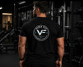 Man wearing black Vida Fit Classic Tee showing large back logo print in gym